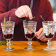 Person assembling cocktails at home in three glasses